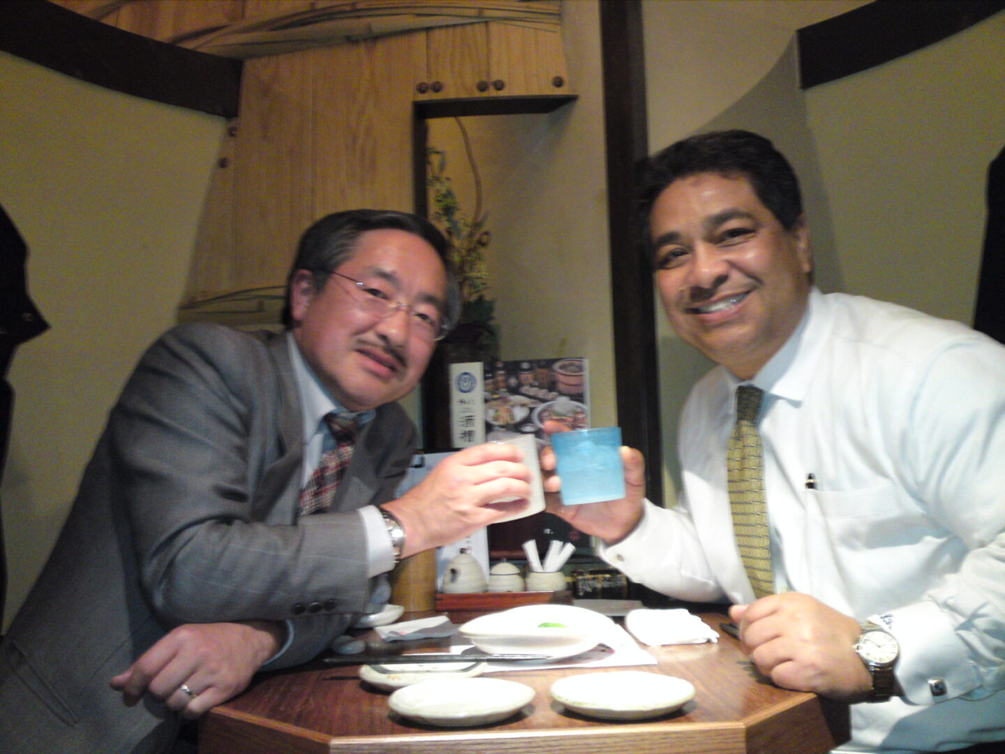 Two men sitting at a table with drinks.